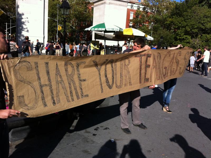 Protesters holding banner: "Share Your Teargas Story"