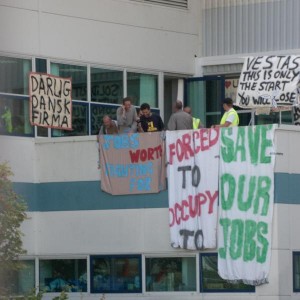 Workers occupying the Vestas wind turbine factory on the Isle of Wight hang banners from a second-floor balcony. Photo by Darran Gange.